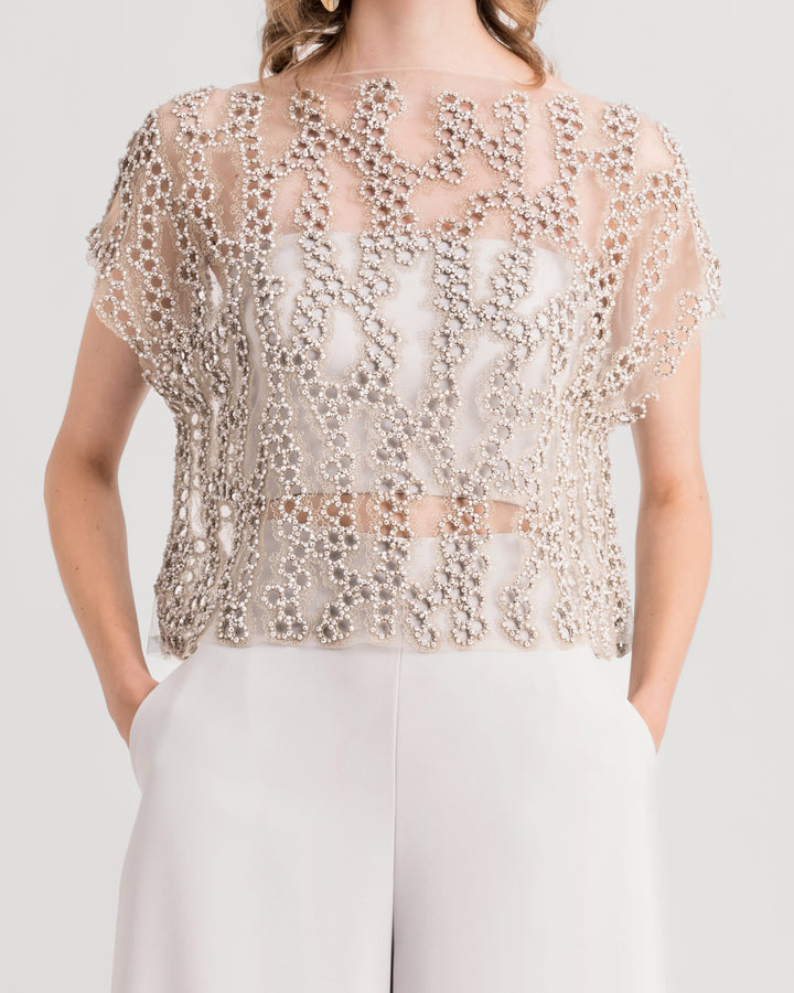 A close up of a grey evening wear featuring embroidered tulle top paired with straight-cut pants.