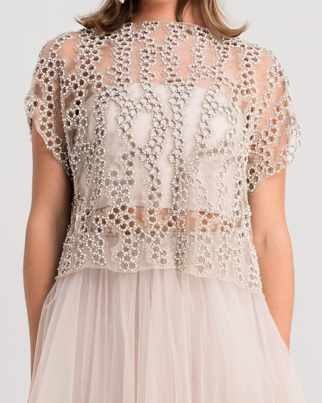 A close-up of a grey evening wear set featuring an embroidered tulle top paired with a midi tulle skirt.