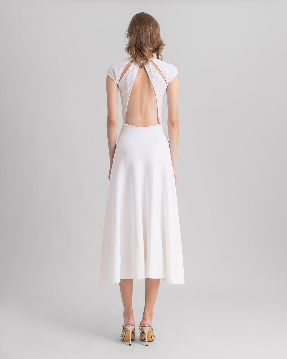 The back of a white midi knit dress featuring cut-outs on the shoulders and an open back.