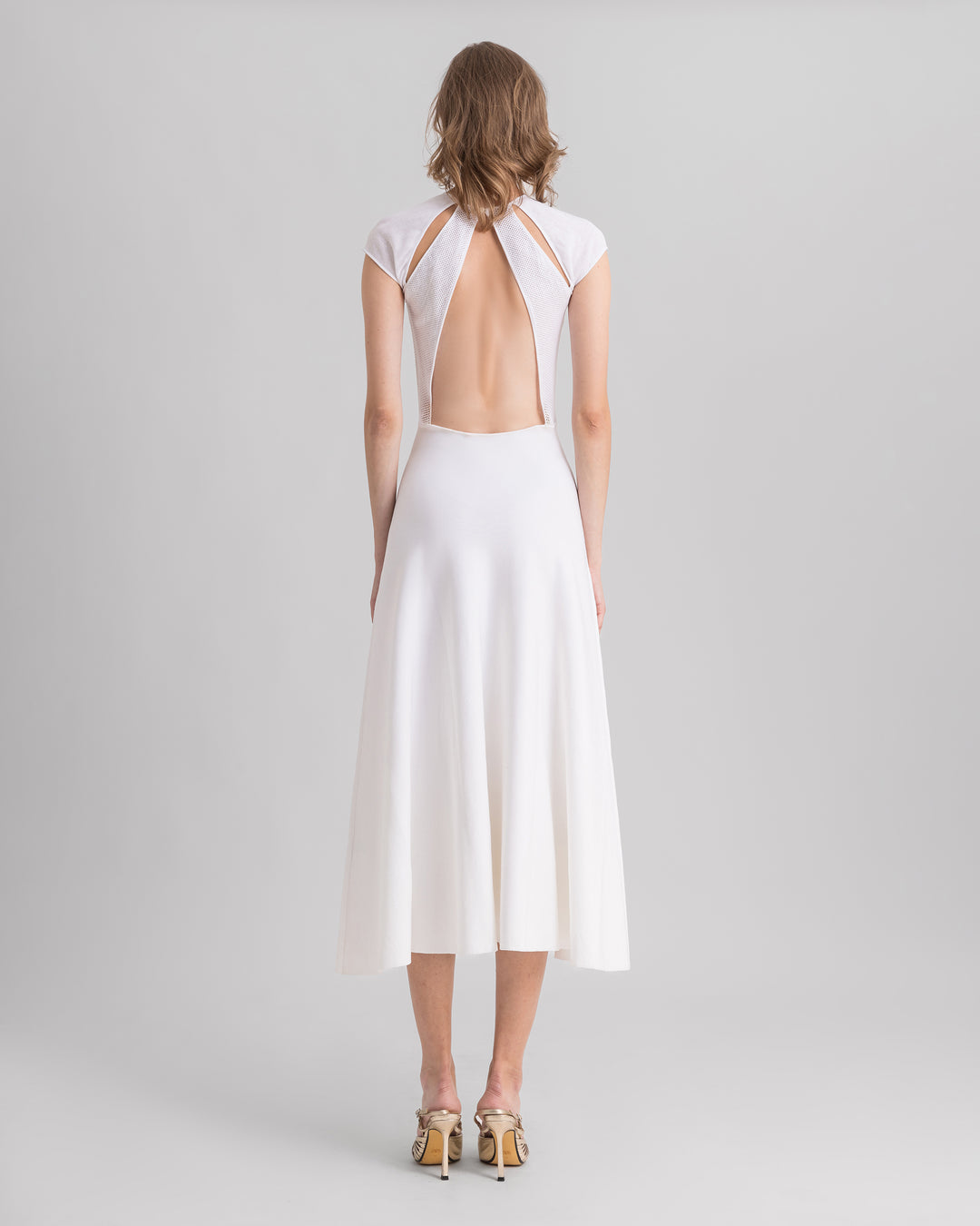 The back of a white midi knit dress featuring cut-outs on the shoulders and an open back.