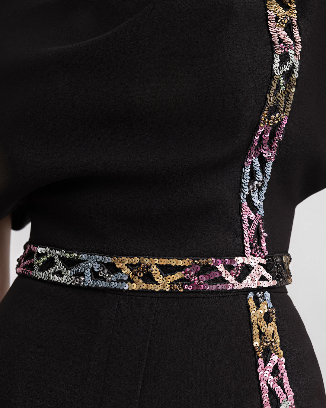 A close-up of a black evening wear set featuring multicolored beading details.