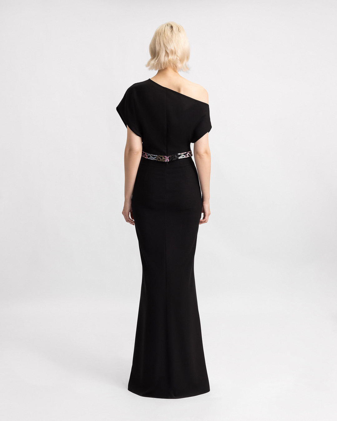 The back of an asymmetrical neckline top with multicored beading belt, paired with a black crepe skirt.