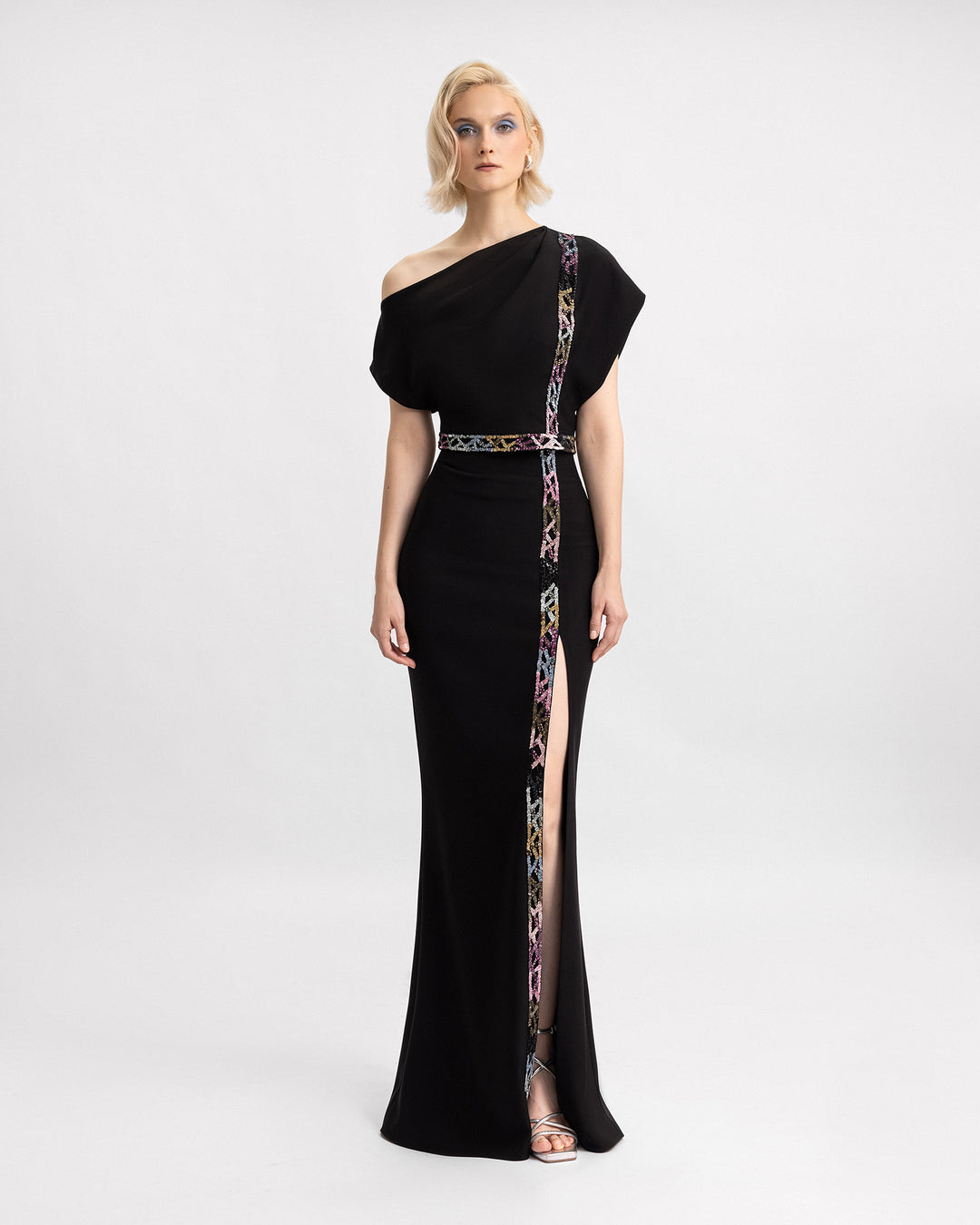 An asymmetrical neckline top with multicored beading details, paired with a beaded skirt featuring a slit on the side.