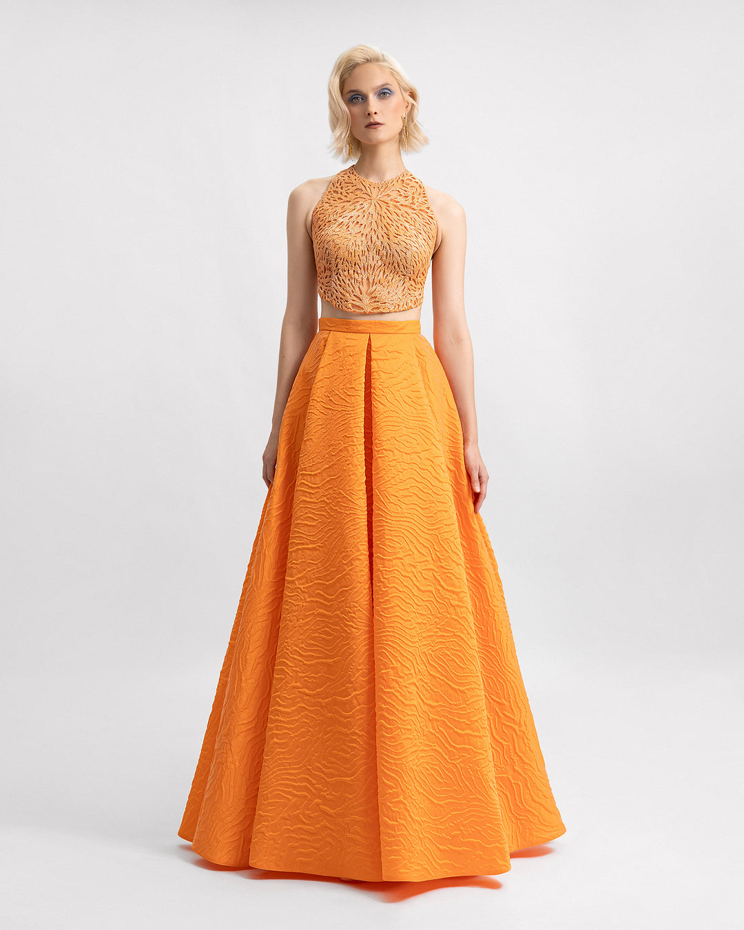 An orange evening wear set featuring a halter-neckline beaded top paired with a draped long jacquard skirt.