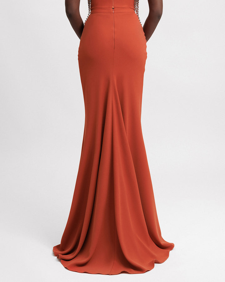 The back of an evening wear slim-cut long crepe skirt in orange color.