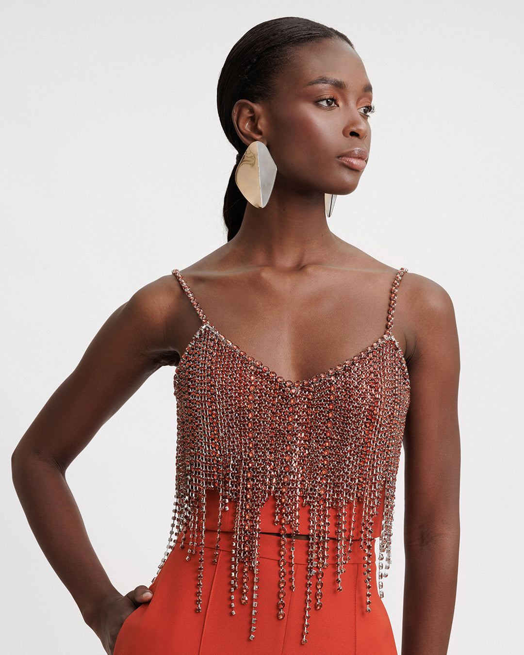 An evening wear set featuring a beaded tassels cropped top in copper paired with an orange pants.