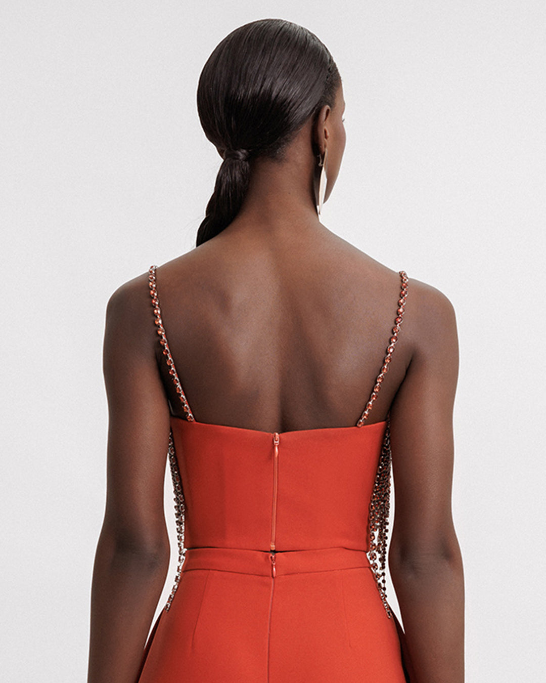 The back of an evening wear set featuring a beaded traps cropped top in copper paired with an orange pants.