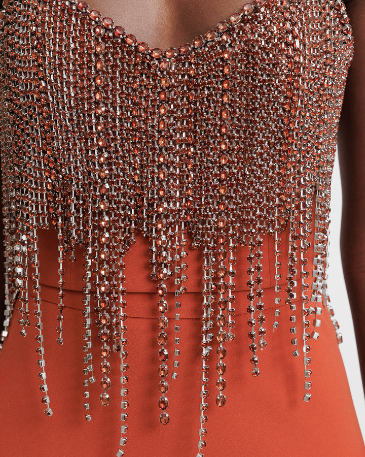 A close-up of a beaded tassels cropped top in copper.