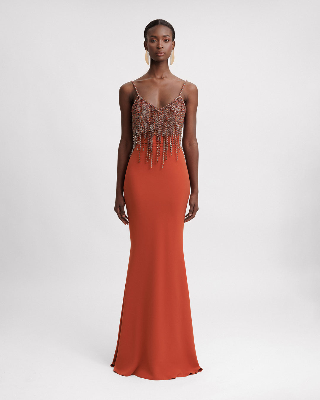 An evening wear set featuring a beaded tassels cropped top in copper color paired with a slim-cut long crepe skirt.