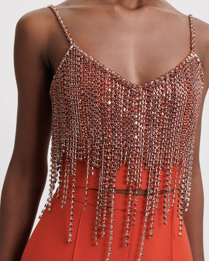 A close-up of an evening wear set featuring a beaded tassels cropped top in copper paired with an orange pants.