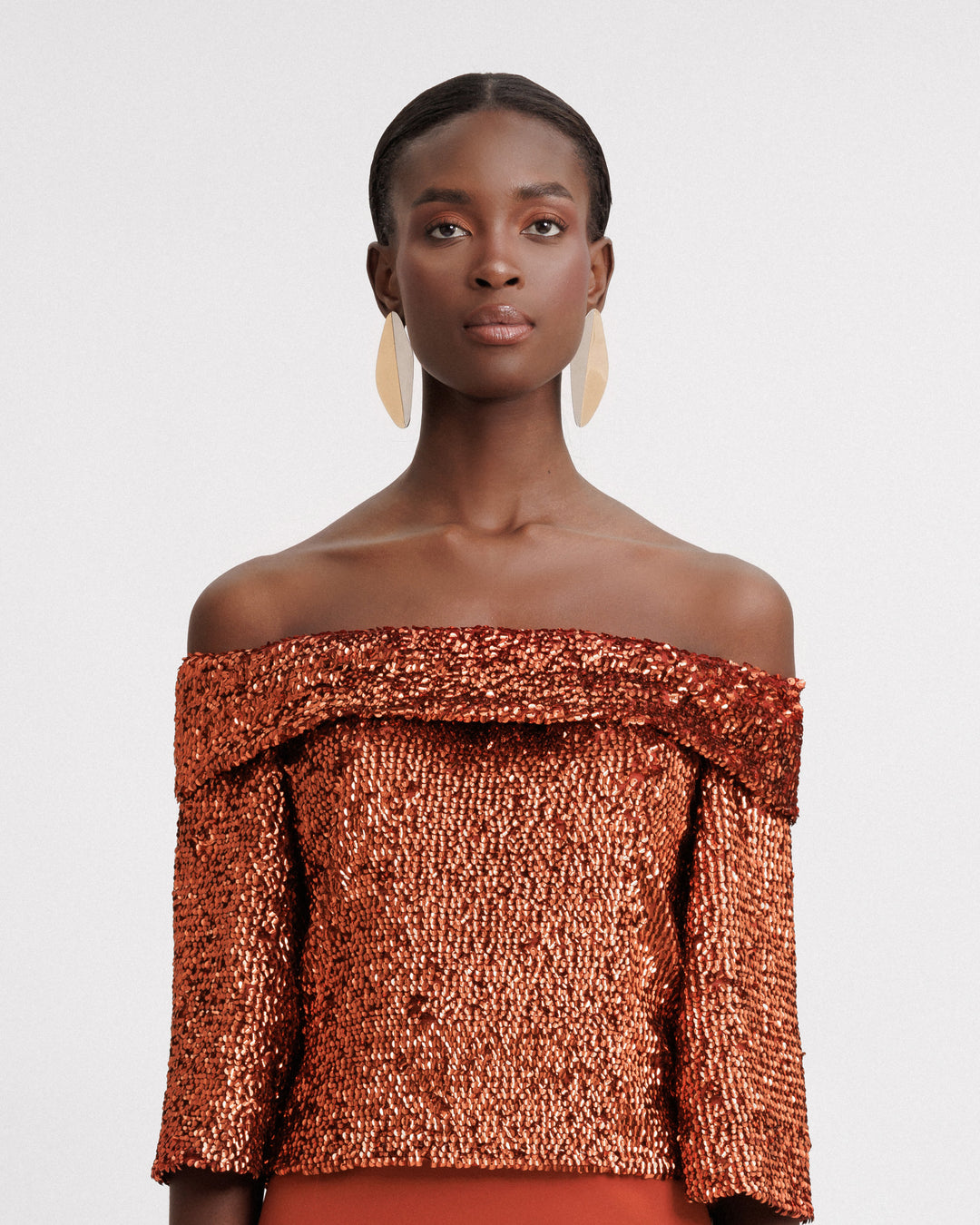 An evening wear set featuring an off-the-shoulders copper sequins top.