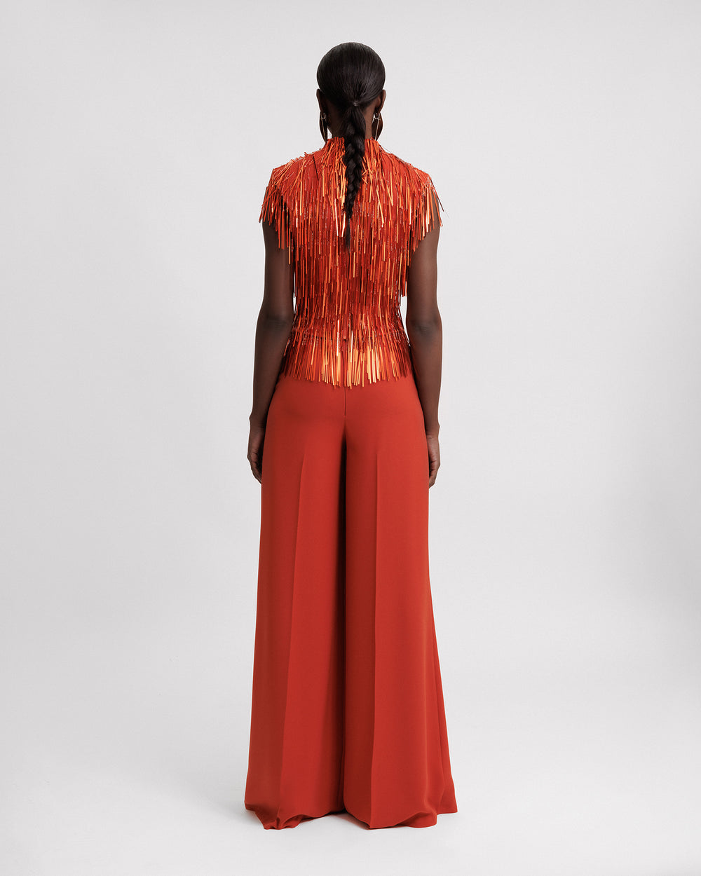 The back of an evening wear set featuring a high-collar beaded fringes top in copper color paired with flared pants.