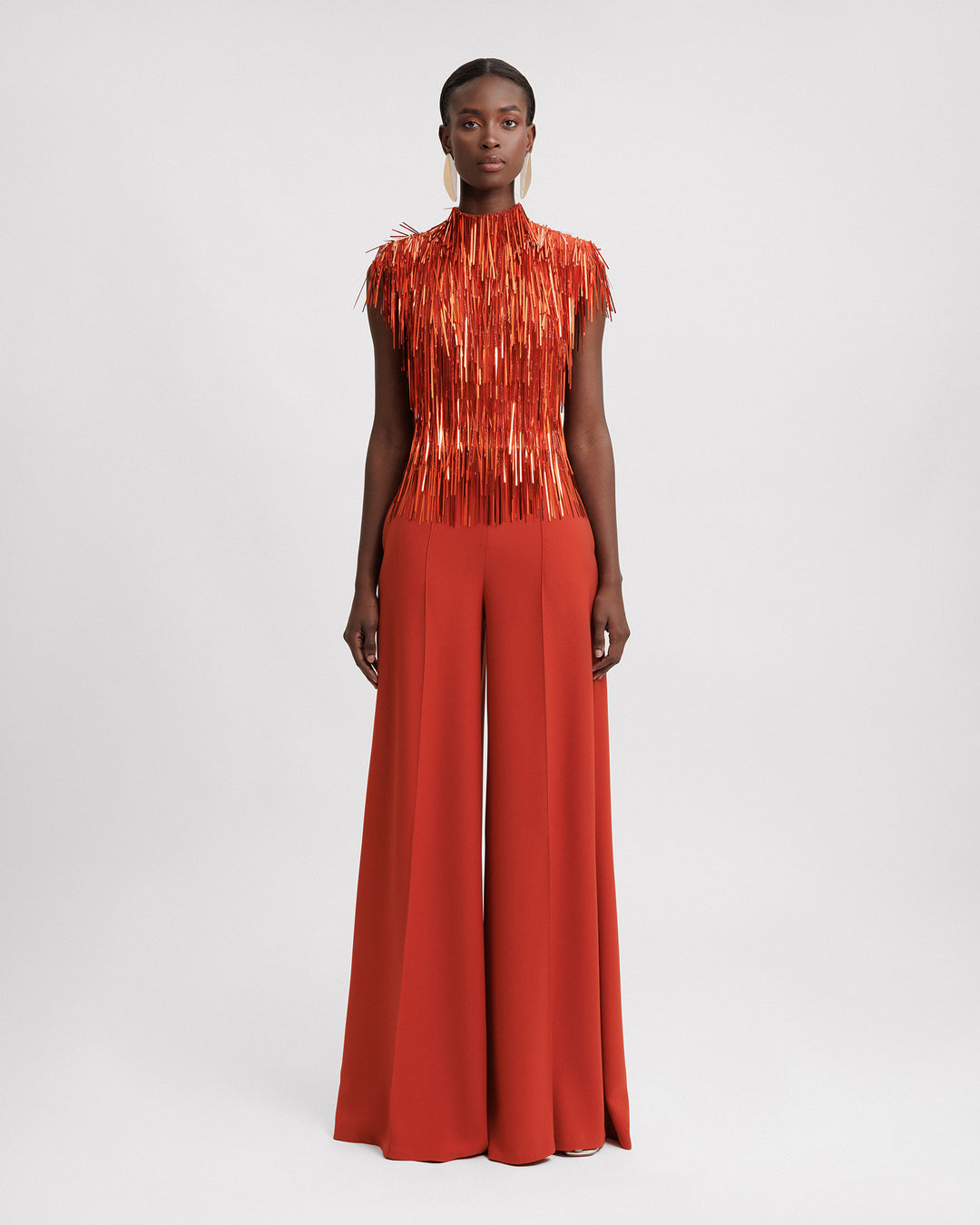 An evening wear set featuring a high-collar beaded fringes top in copper color paired with flared pants.