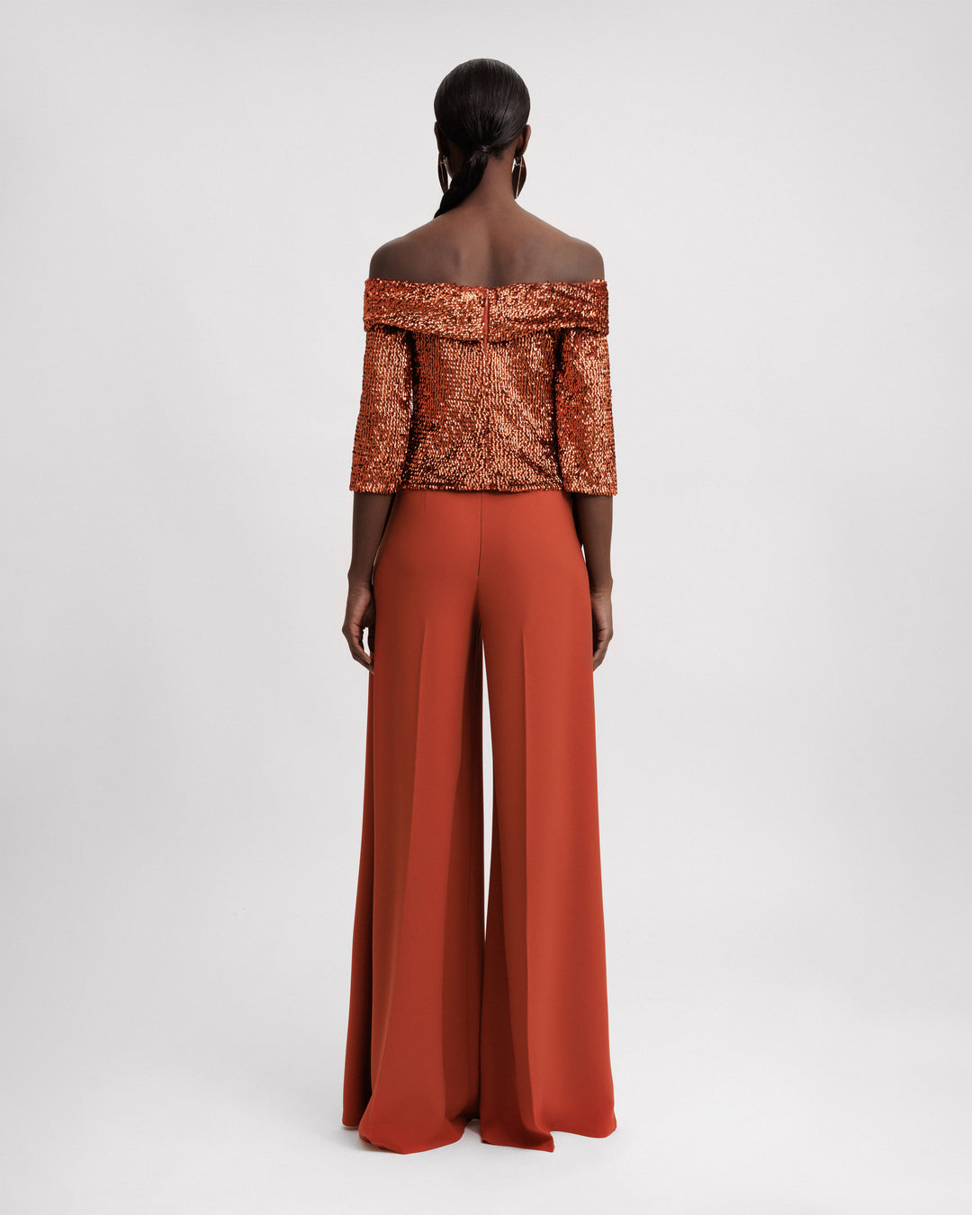 The back of an evening wear set featuring an off-the-shoulders copper sequins top paired with a flared pant.