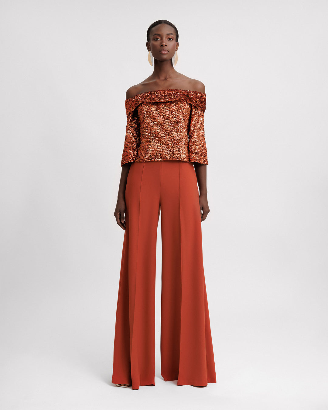 An evening wear set featuring an off-the-shoulders copper sequins top paired with a flared pant.