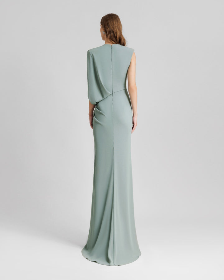 The back of an asymmetrical teal evening dress with a bolero-like sleeve and a draped skirt .