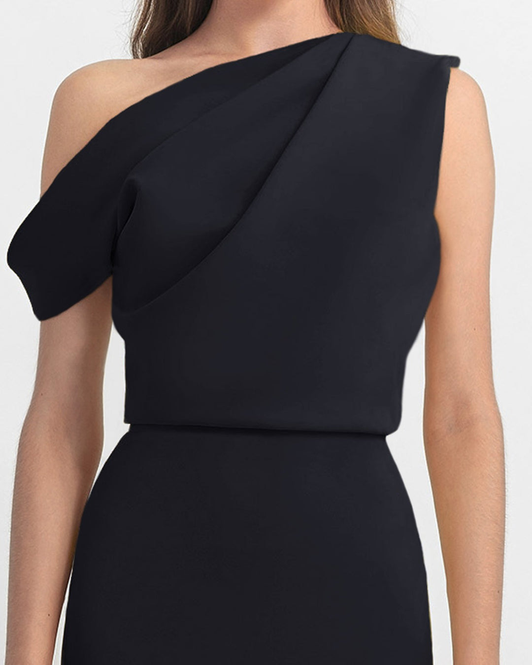 A close-up of an asymmetrical cut crepe long black dress with draping details on the upper part and a slim cut skirt.