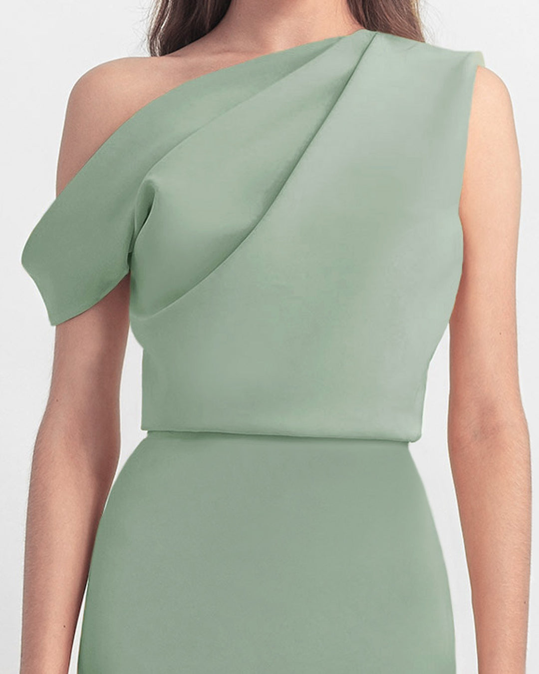 A close-up of an asymmetrical cut crepe long mint green dress with draping details on the upper part.