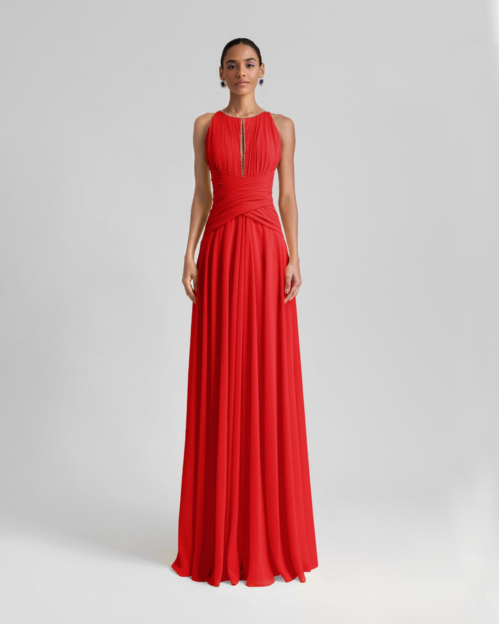 A long red dress featuring draping on the waist, beaded neckline and an open back.