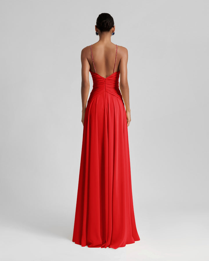 The back of a long red dress featuring draping on the waist and an open back.