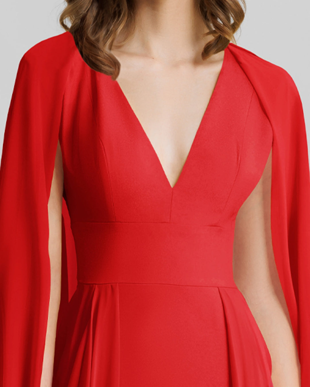 A close-up of a V-neckline long evening red dress with cape-like draped sleeves.