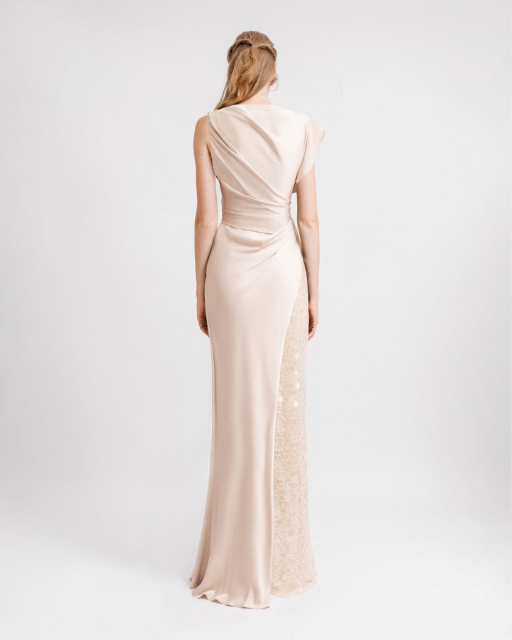 The back of an asymmetrical draped satin dress in champagne color with a side sequin skirt.