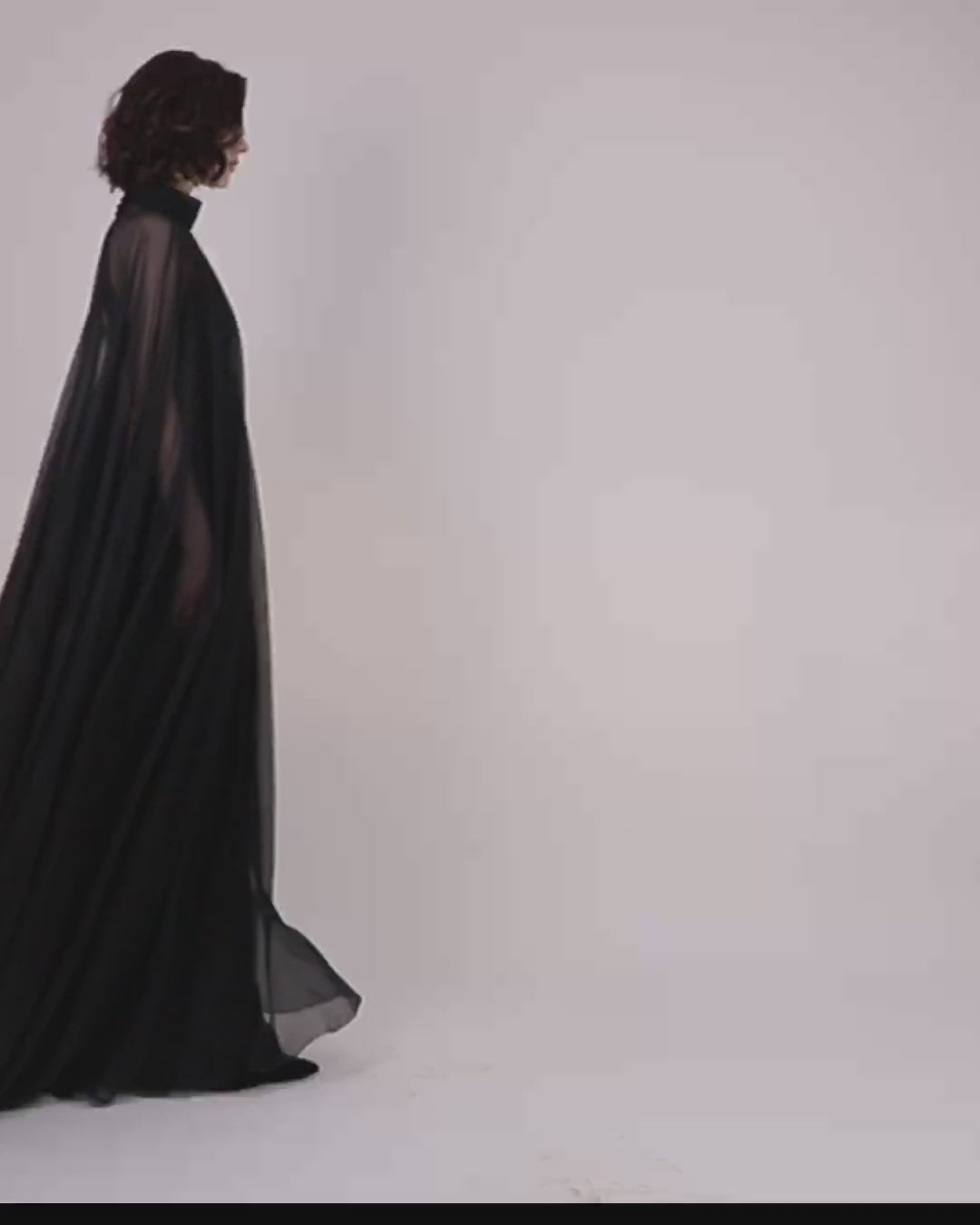 A slim cut crepe long black evening dress with see through overlayered cape.