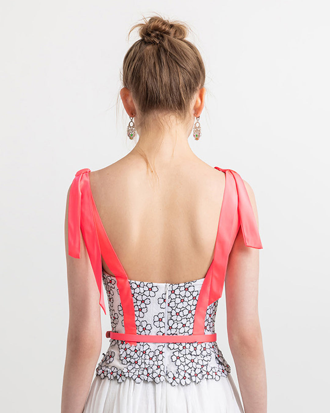 The back of a V-neckline top with pink bow details on the shoulders, and a detachable pink belt.