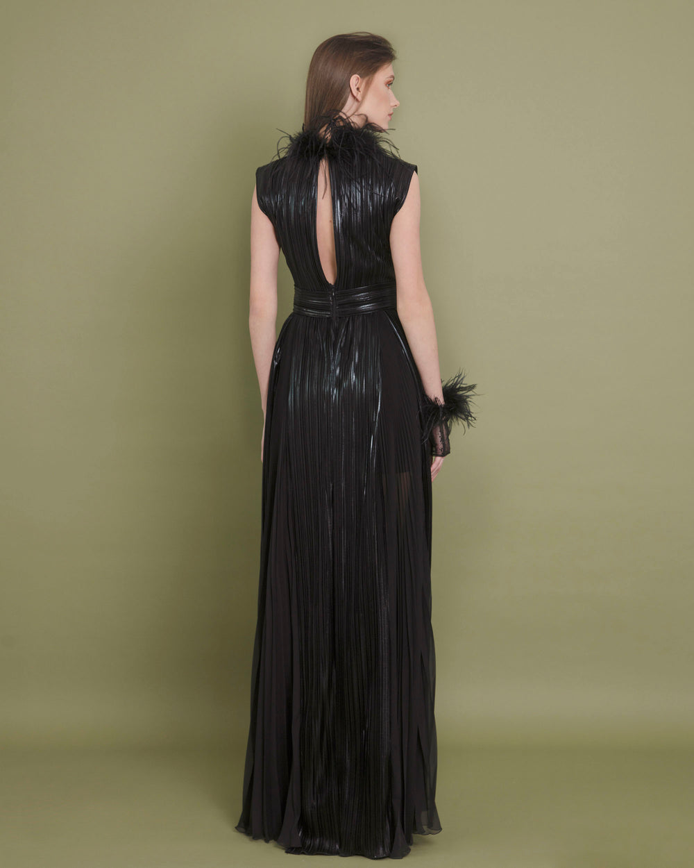 The back of a fully pleated black evening dress with feather details on the neck and a slight opening at the back.