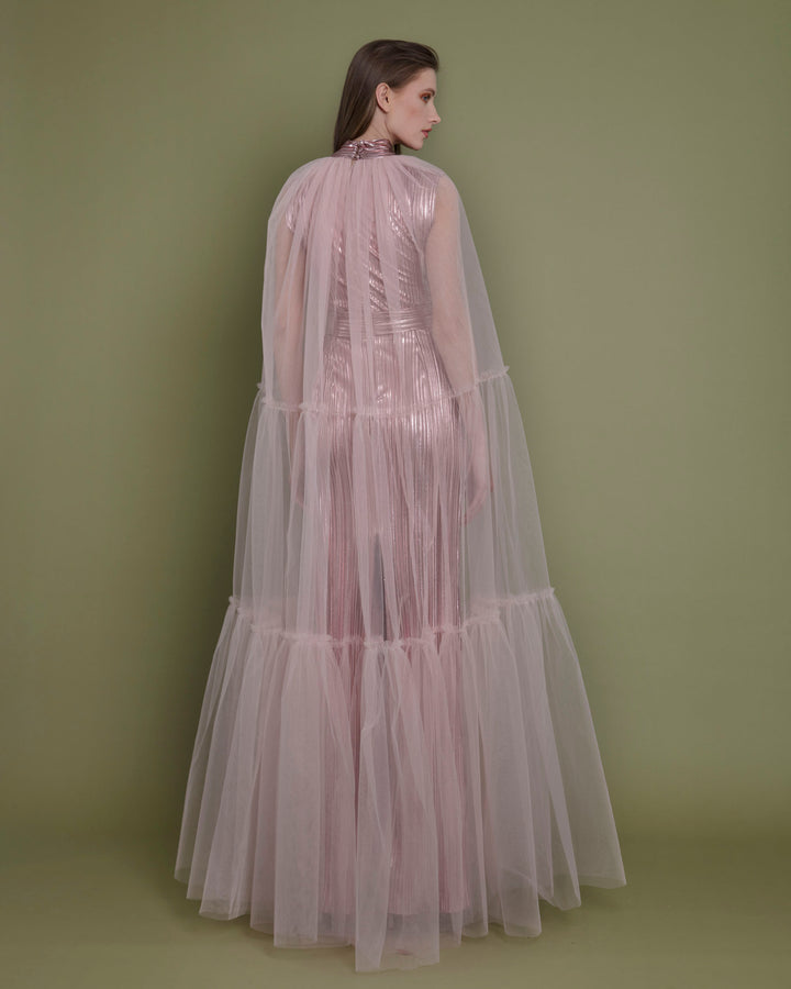 The back of a slim cut metallic pink evening dress in pleated fabric paired with a tulle ruffled cape.