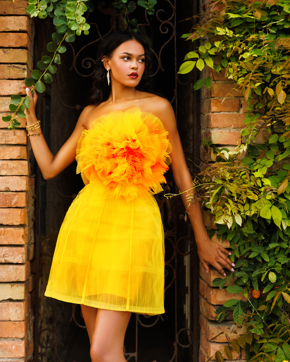 A yellow evening wear set featuring a flower draped tulle corset, paired with a cage design mini skirt.