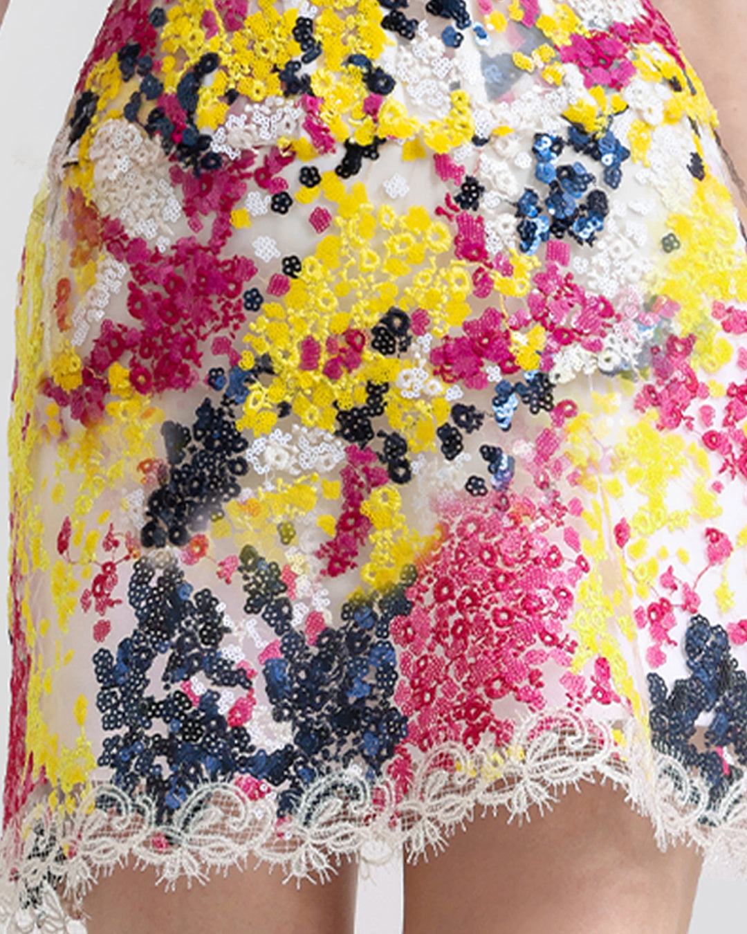 A close-up of a  multicolor embroidered sequins short skirt with lace hemline.