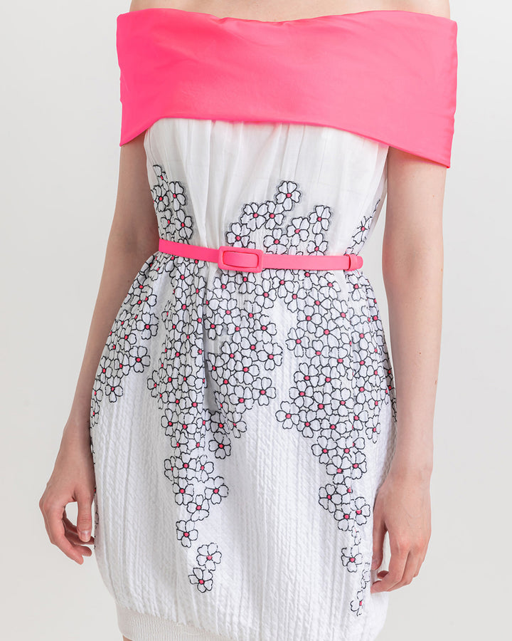 A close-up of an off-shoulder dress with floral details, paired with a pink detachable belt.