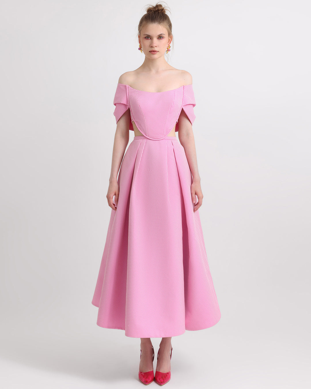 An off-shoulder pink jacquard dress with draping and cut-out details on the sides.