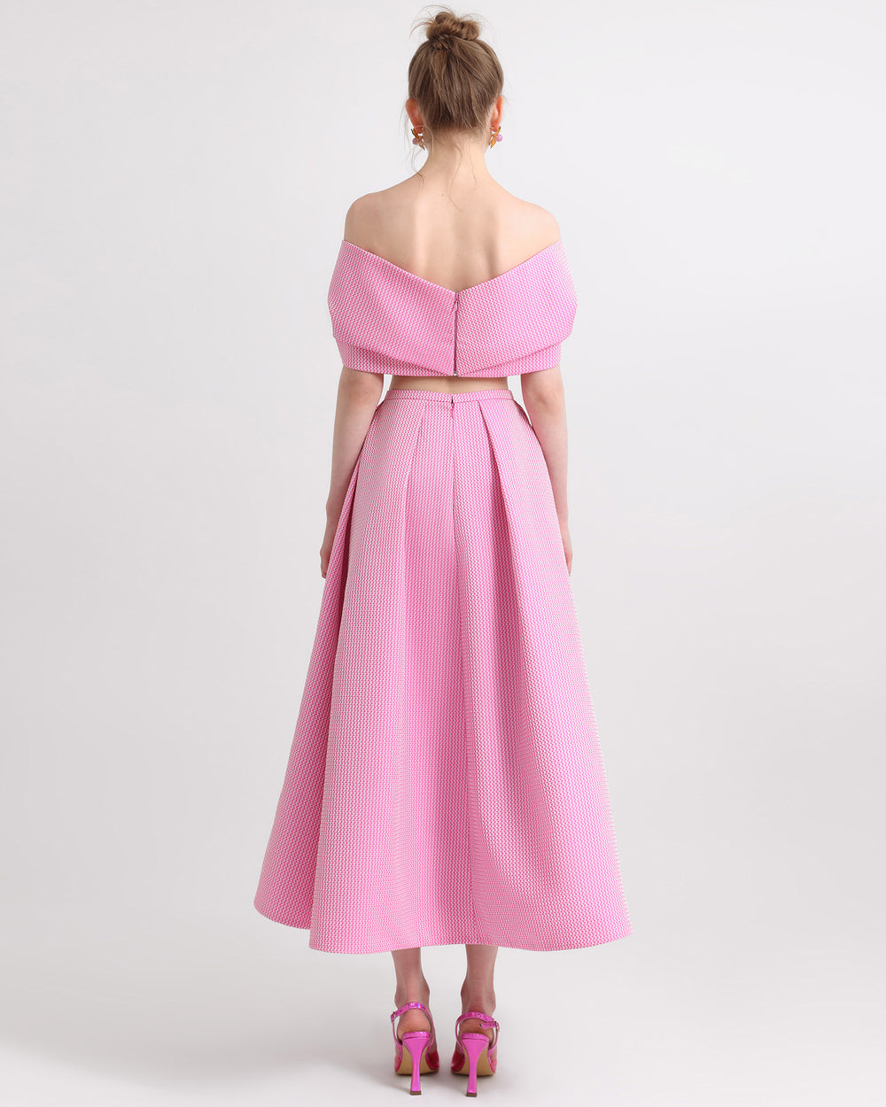 The back of an off-shoulder pink jacquard dress with draping and cut-out details on the sides.