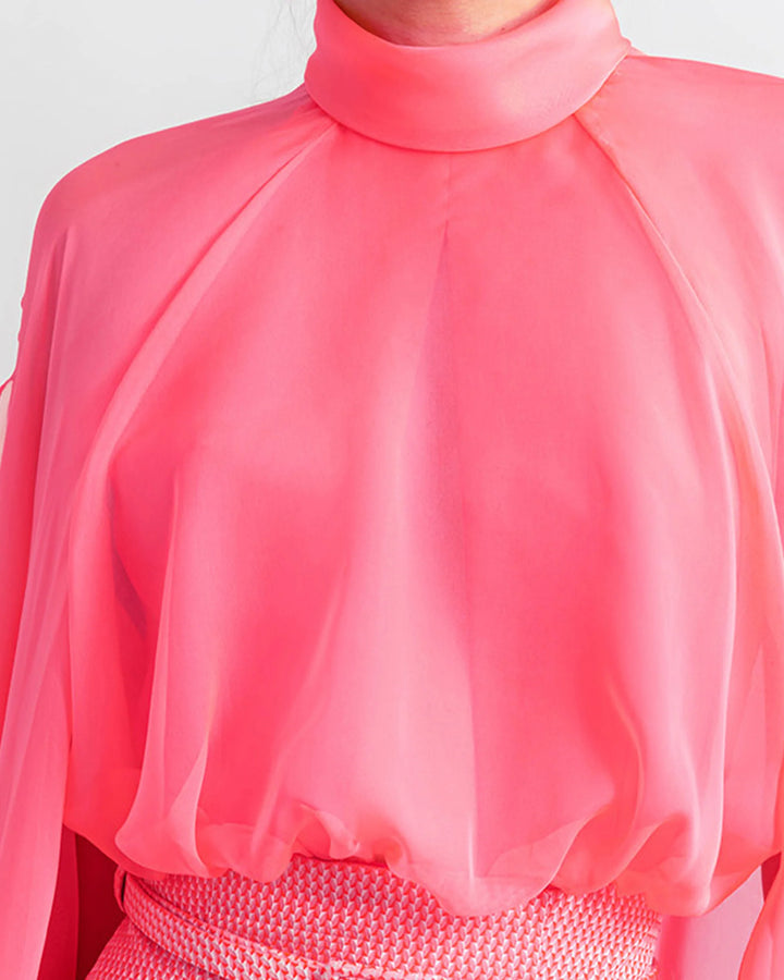 A high-neckline pink top with long sleeves close-up.