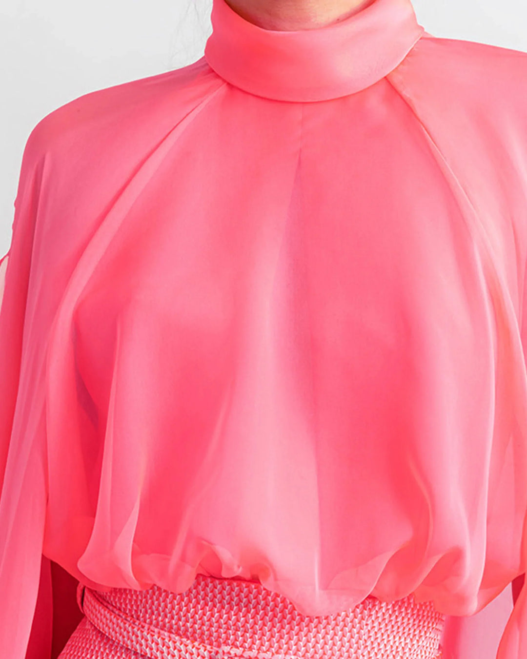 A high-neckline pink top with long sleeves close-up..