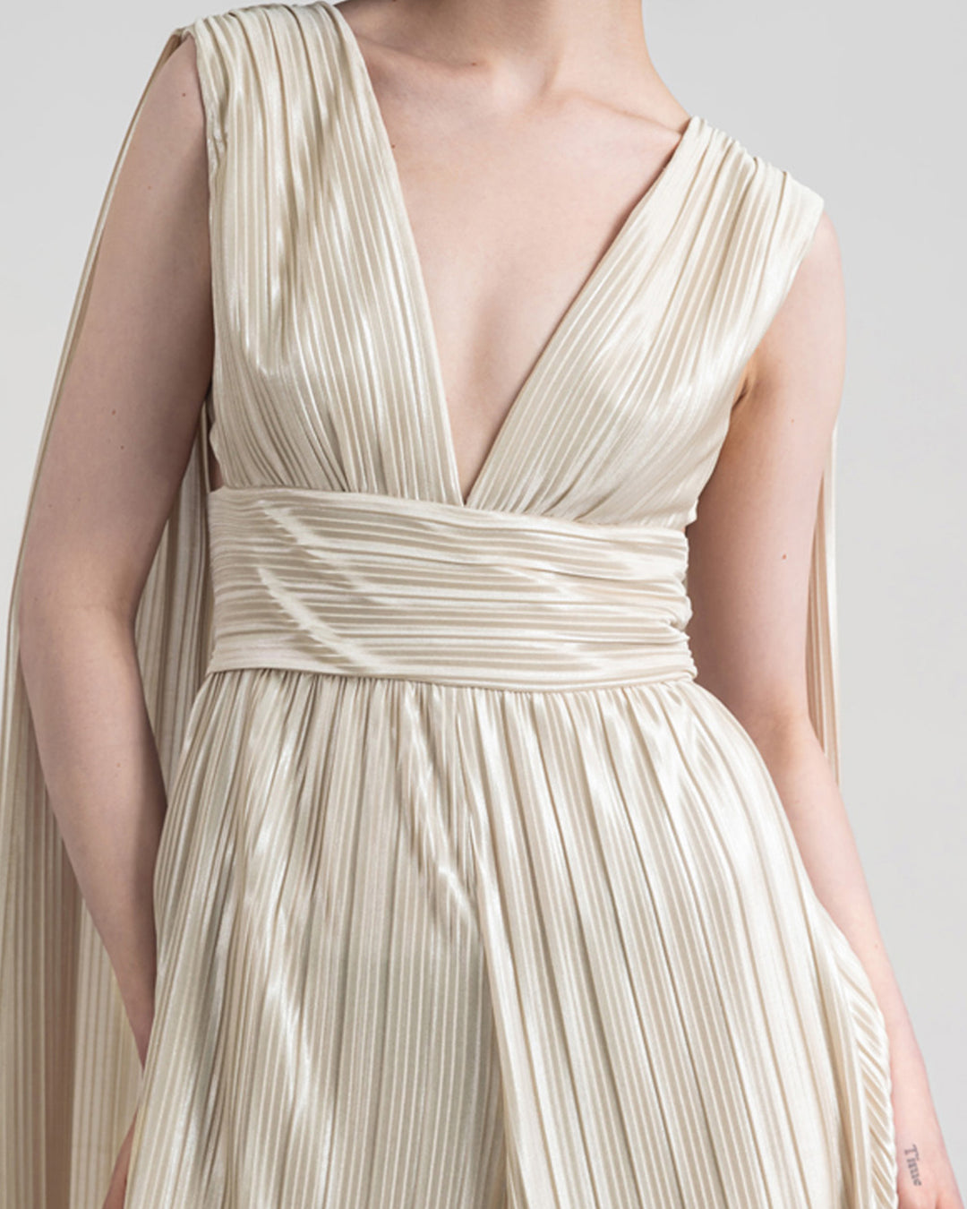 A close-up of a deep v-neckline, flare cut legs with cape-like design from the back.