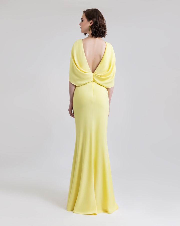 A deep V-shape open back long yellow evening dress with cape-like sleeves.