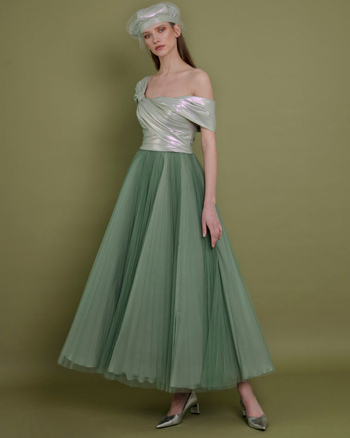 A wide cut midi evening dress featuring an asymmetrical neckline with metallic latex bow-like design and a pleated green tulle skirt.