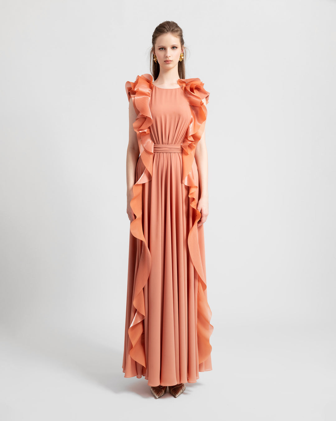 A flowy crepe copper evening dress featuring symmetrical ruffled details on the sides from the shoulders all the way down to the hemline.