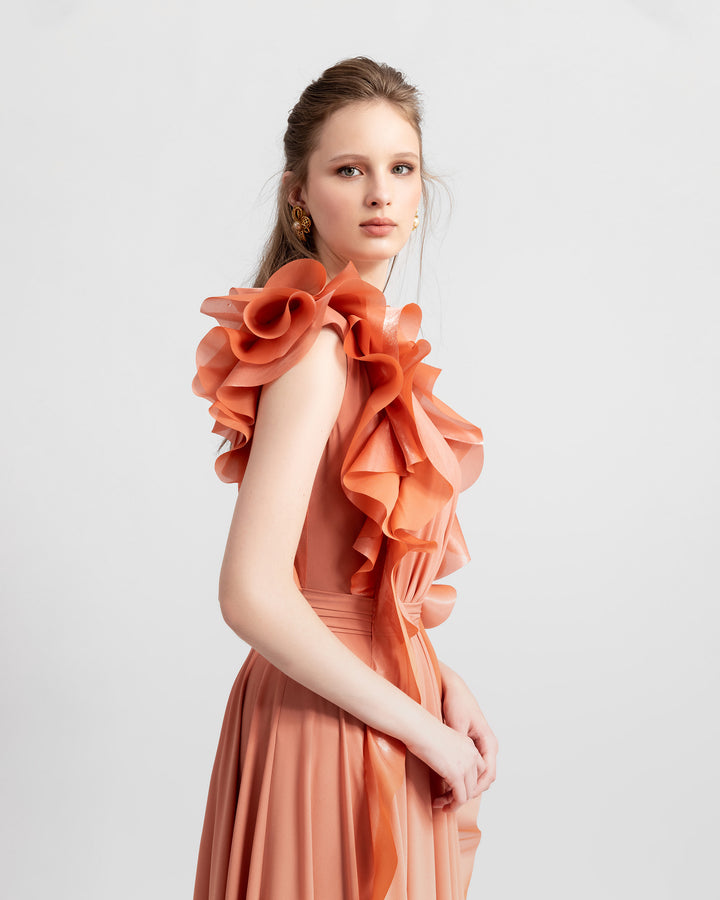 A flowy crepe copper evening dress featuring ruffled details on the sides from the shoulders all the way down.