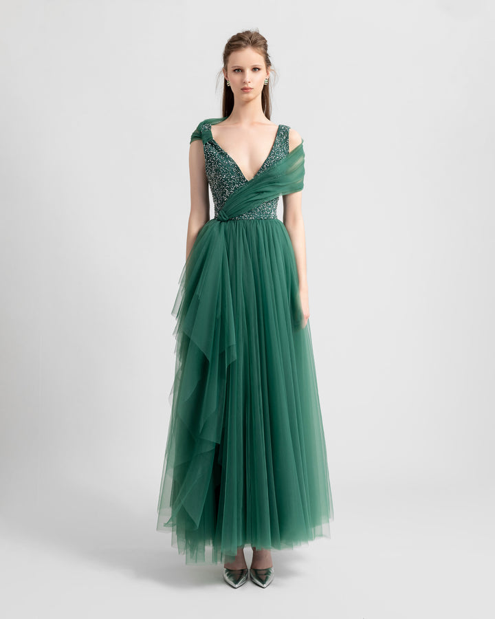 A deep v-neckline a-cut green tulle evening dress with beading on the bust and ruffled tulle on the skirt.