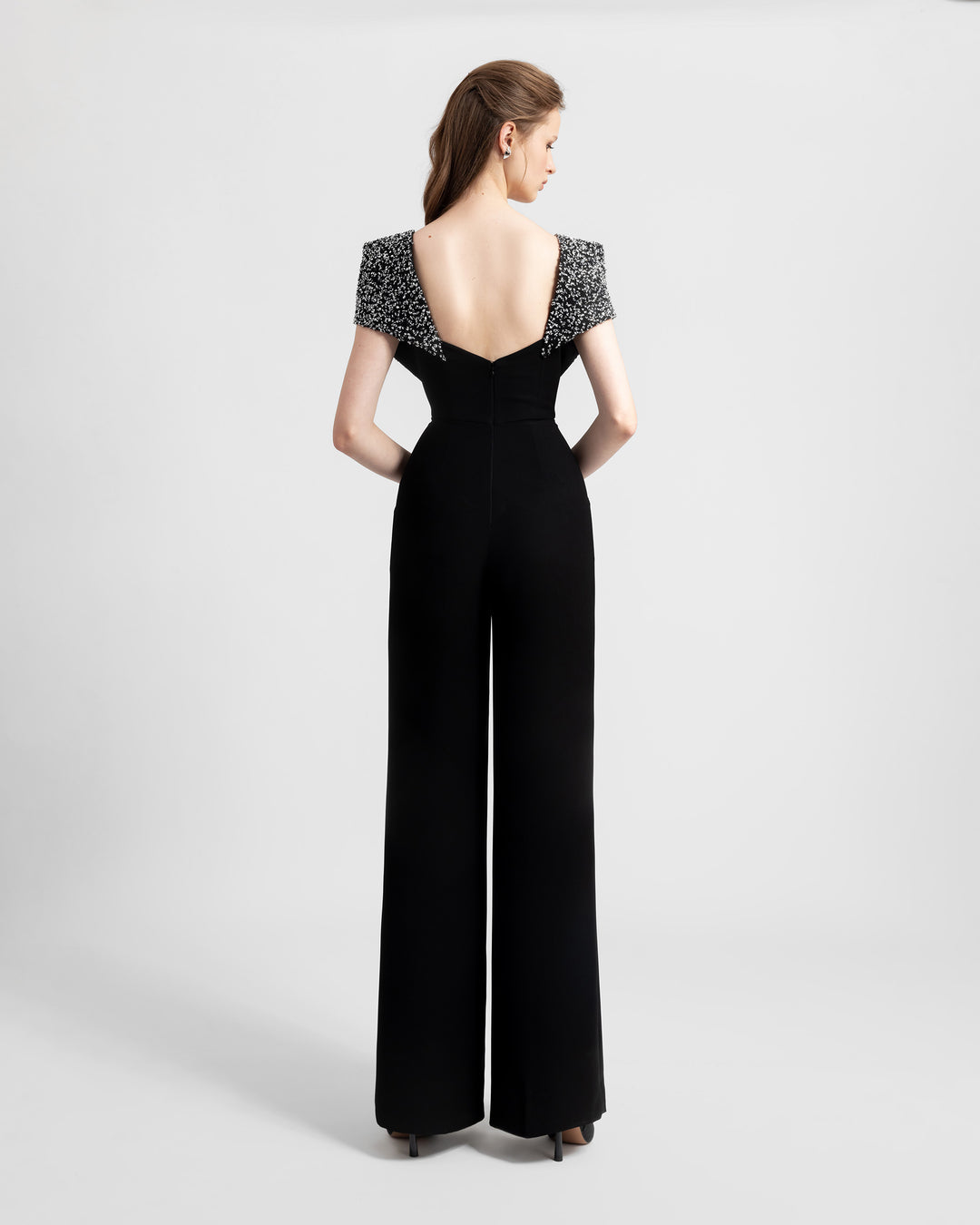 The back of a straight-cut black crepe jumpsuit featuring fully beaded shoulders and an open back.