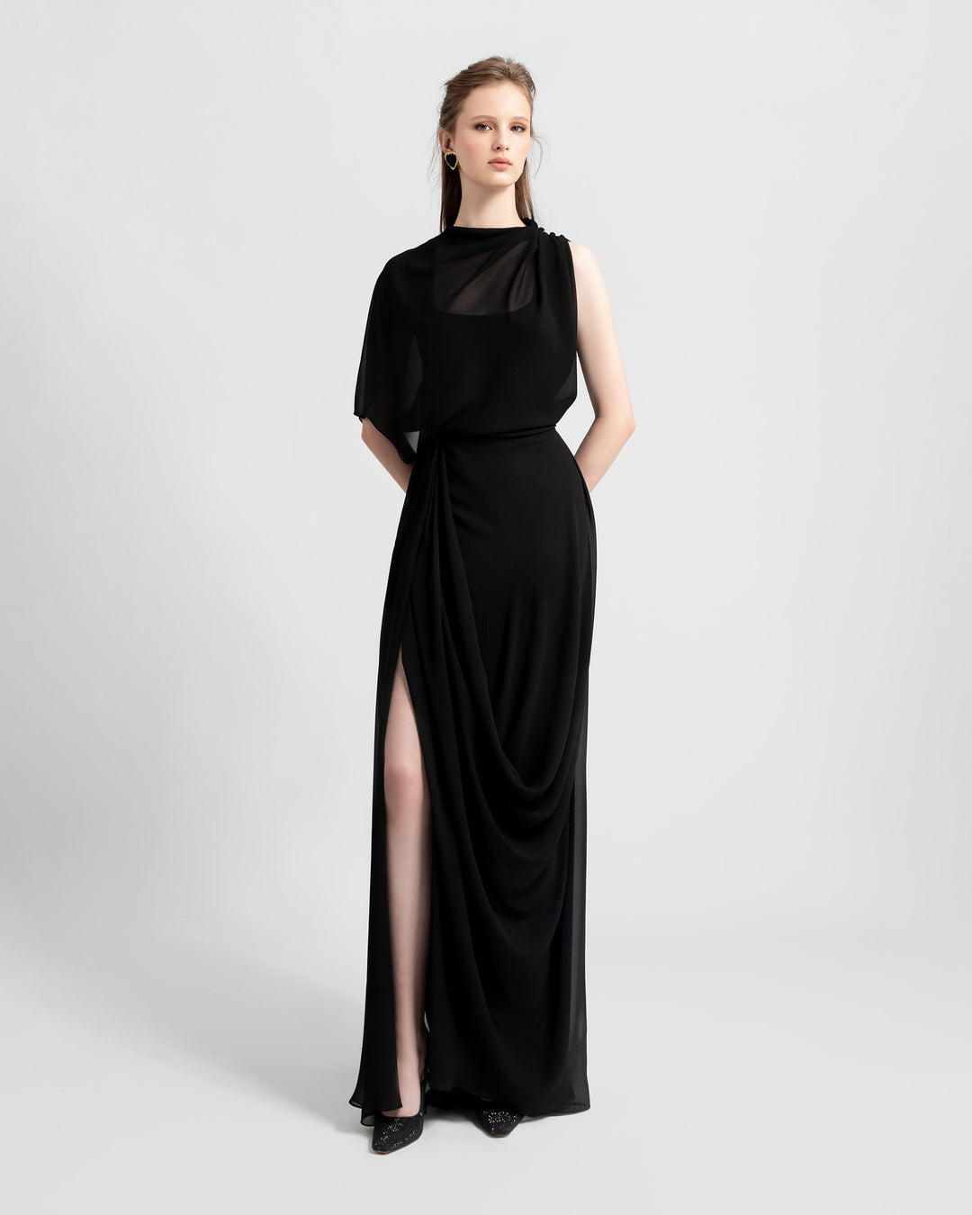 An asymmetrical chiffon black dress with one sleeve and draping details featuring a slit on the side.