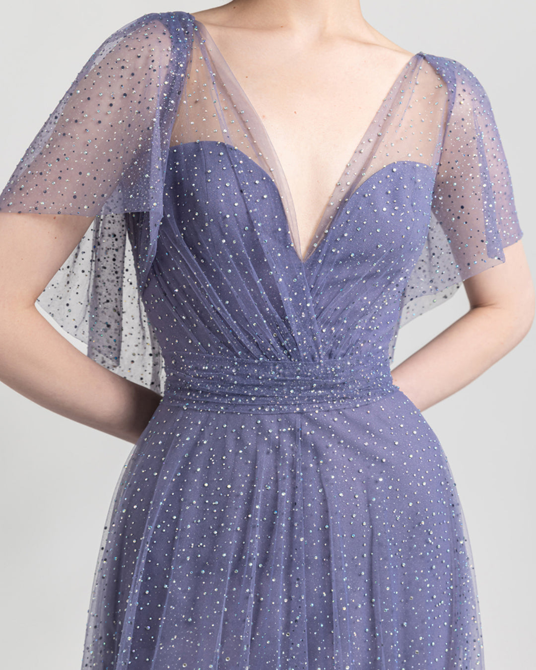 A close-up of a V-cut neckline flared lilac evening dress with draping details on the waist, and short sleeves.