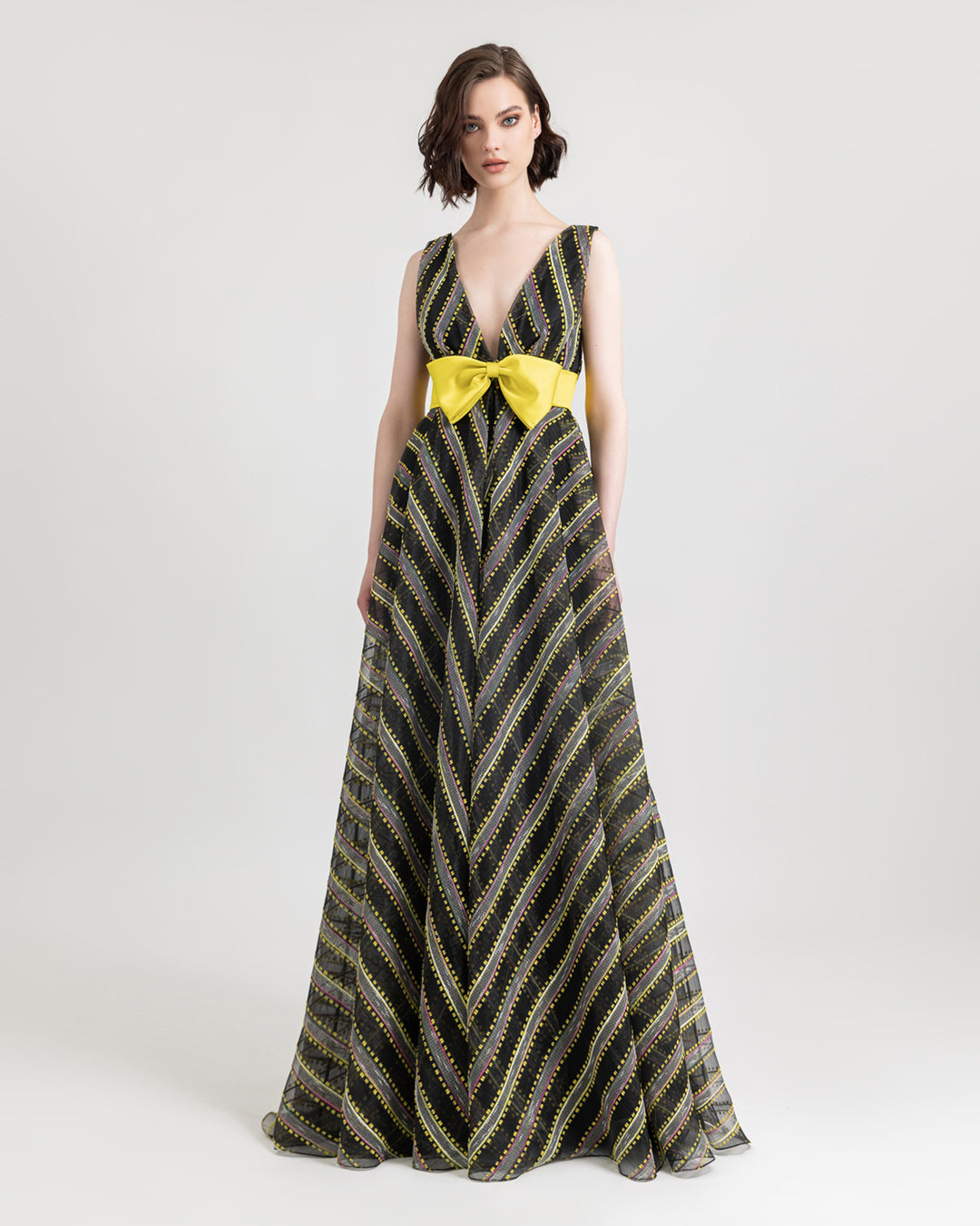 A deep V-neckline flared evening dress with a yellow bow-like design in the middle.