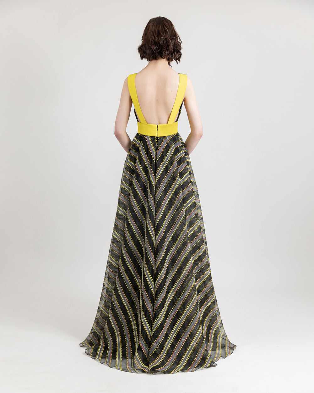 An open back flared evening dress with yellow trips and waist band.