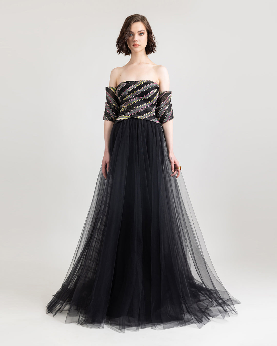 An off-the-shoulder evening dress with draping  on the bust and a flared black tulle skirt.