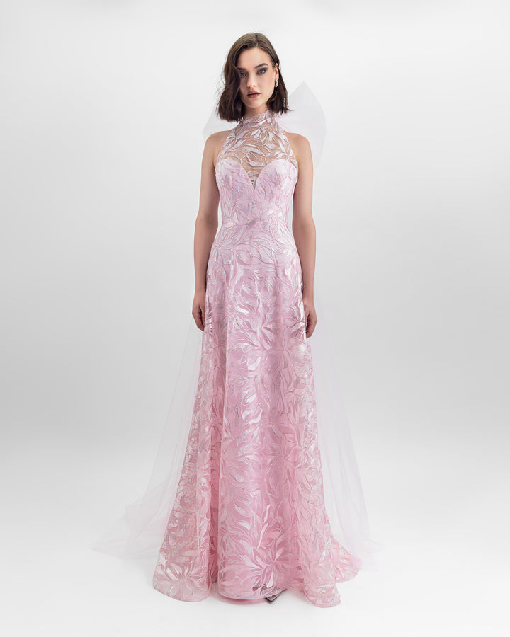 A flared cut embroidered fabric long pink dress with an overlayed halter neckline and a backless design, paired with a detachable tulle cape.